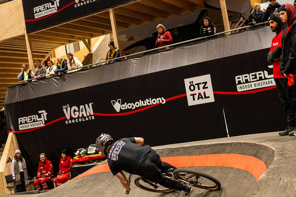 UCI Pump Track WM Tirol: Radfahrer auf der Strecke. Zuschauer und Sponsoren im Hintergrund. #PumpTrack #Tirol #WM