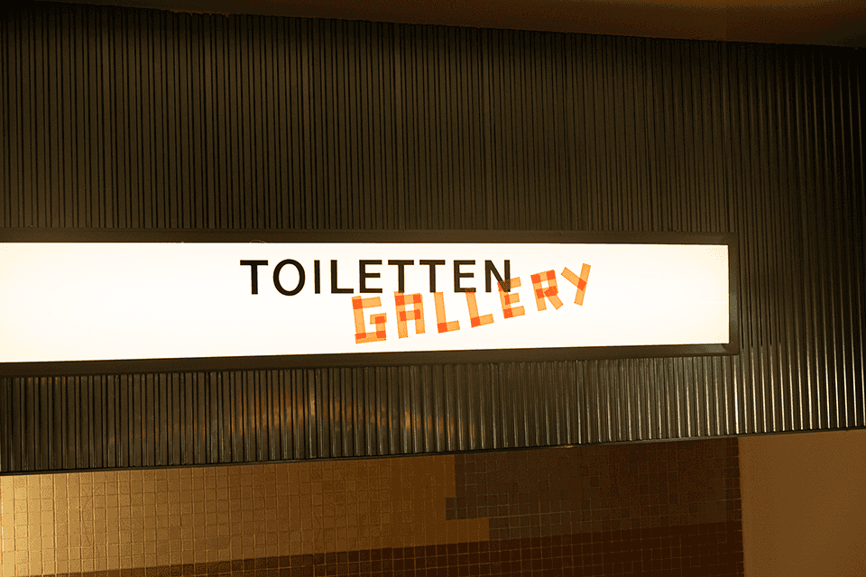 VIVA CON AGUA Toiletten Gallery Schild. Kunstvolle WC-Beschilderung.